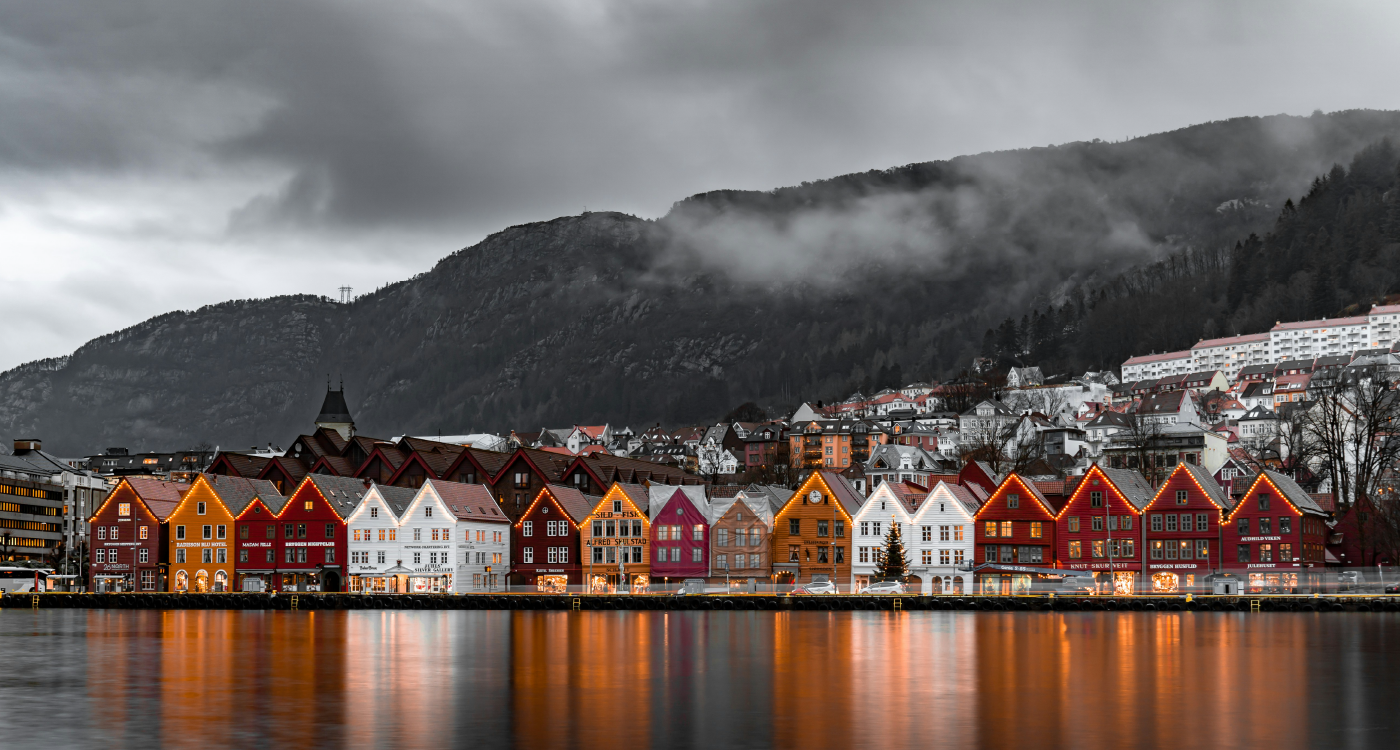 Flere trehus på rekke ved vannet.