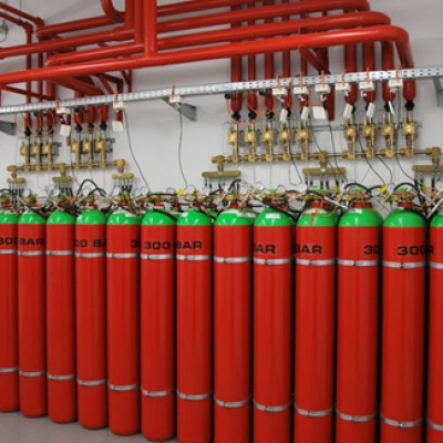 Roede gassflasker staar paa rekke.